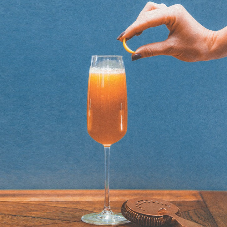 Slice of orange being added to french cocktail